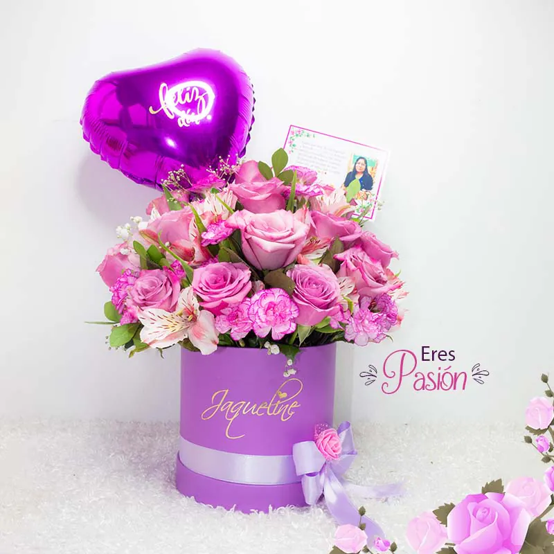 Arreglo floral "Eres Pasión" con rosas y flores en tonos rosados y lilas en caja lila personalizada con globo en forma de corazón y tarjeta.