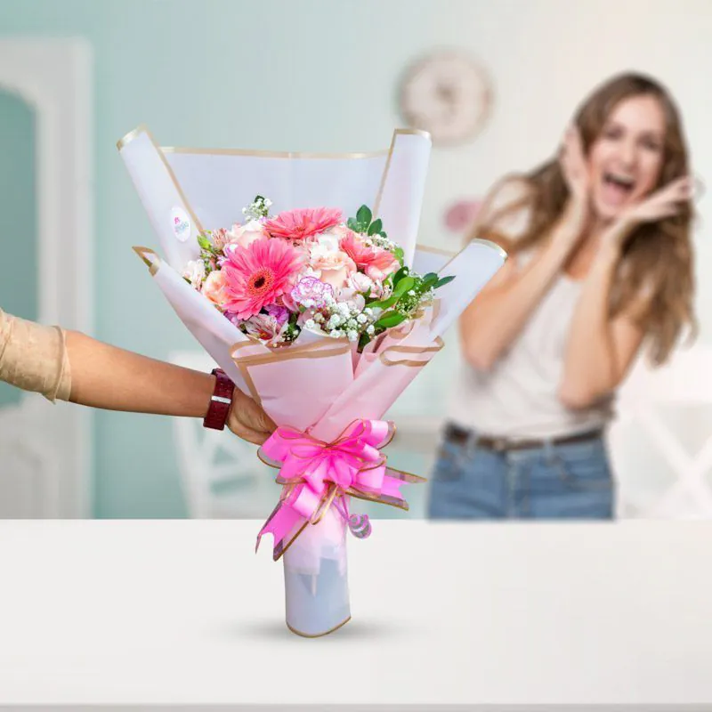 Ramo de flores frescas con gerberas rosas y follaje, entregado con alegría por Florería Amalia en Lima.