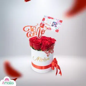Caja personalizada con nombre 'Miriam' y adornos de mariposa, repleta de rosas rojas y con accesorios como tarjeta y adornos 'Te Amo'.
