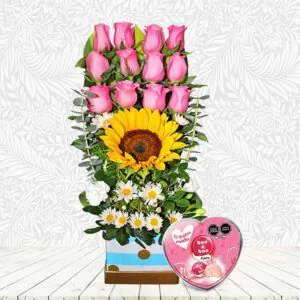 🌹 Arreglo floral "Dulce Amanecer" con rosas rosadas, girasol, margaritas y caja de chocolates. Un regalo vibrante y encantador.