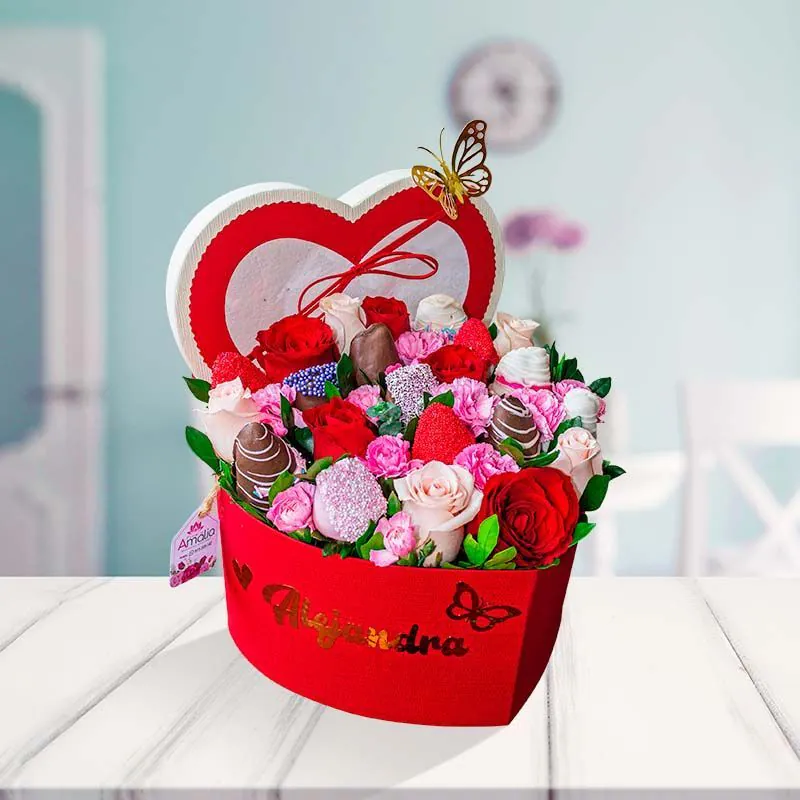 Caja corazón de flores variadas y fresas cubiertas de chocolate con mensaje de feliz aniversario.