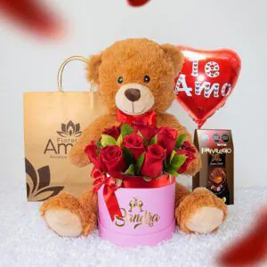 Arreglo de rosas rojas en caja personalizada con el nombre 'Sandra', acompañado de un peluche de oso y chocolates, ideal para un regalo de amor.