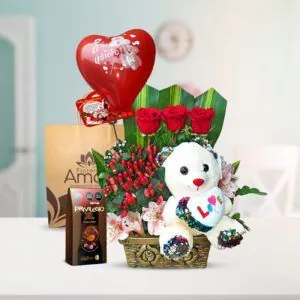Arreglo floral con tres rosas rojas, un peluche blanco con corazón, globo rojo ‘Te quiero’, chocolates Privilegio XL y bolsa decorativa de Florería Amalia