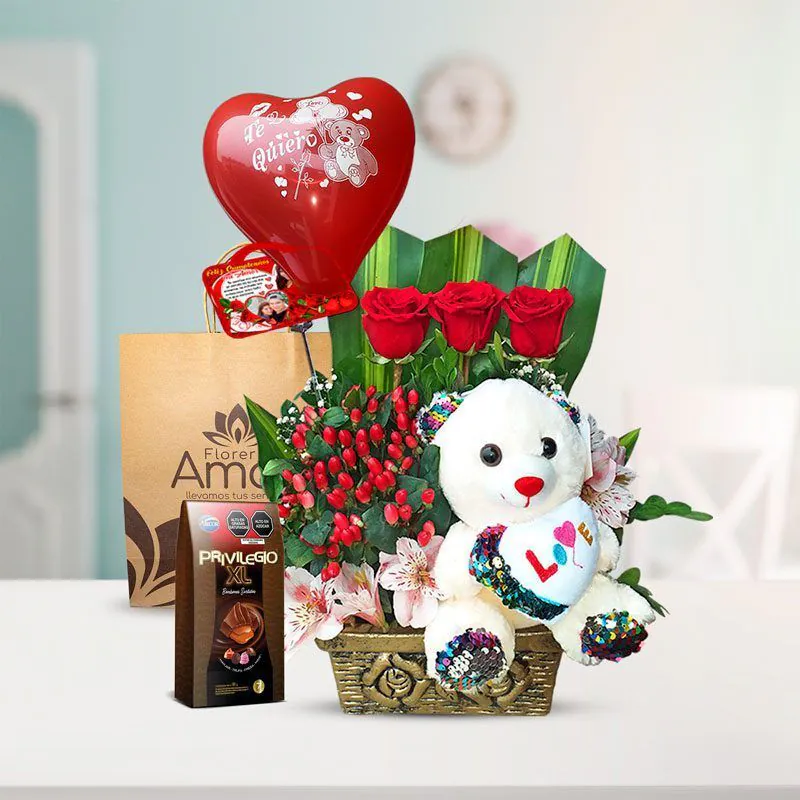 Arreglo floral con tres rosas rojas, un peluche blanco con corazón, globo rojo ‘Te quiero’, chocolates Privilegio XL y bolsa decorativa de Florería Amalia