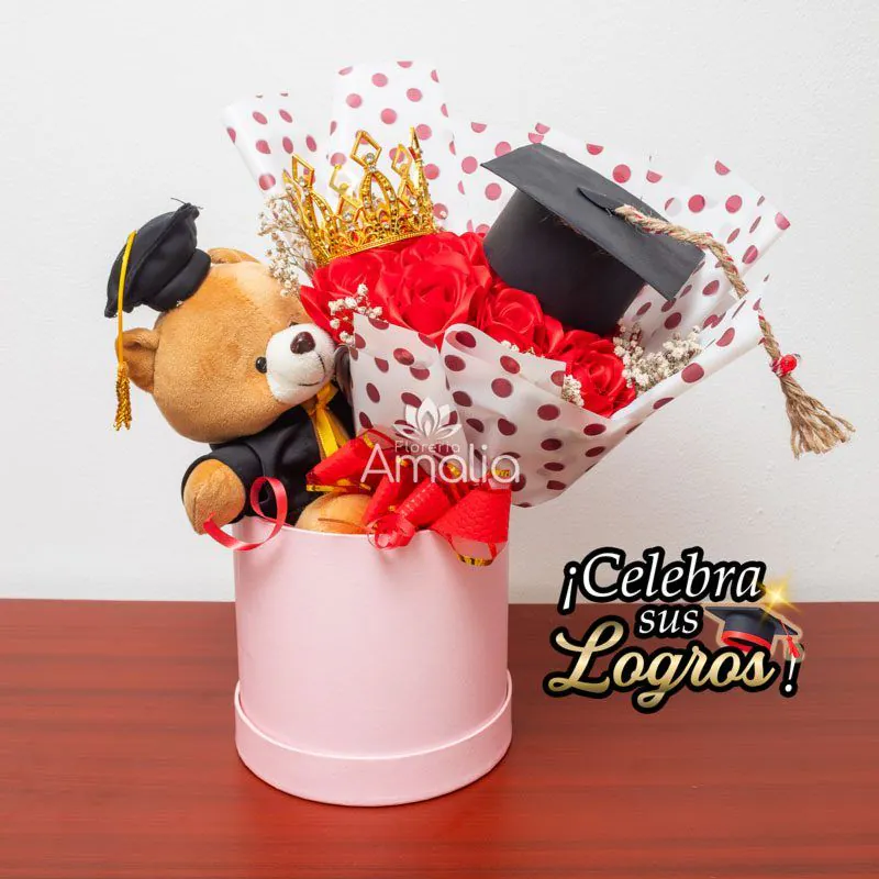 Caja decorativa con peluche de graduación, corona dorada y rosas rojas, ideal para celebrar logros académicos.