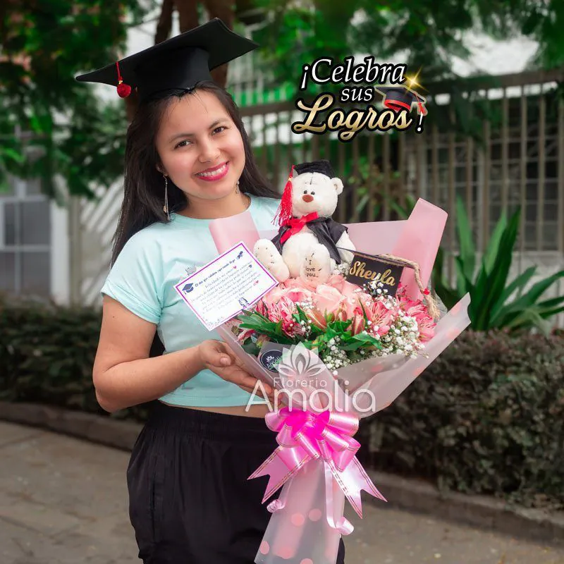 Ramo de flores rosadas con peluche de graduación personalizado, tarjeta de felicitación y detalles decorativos en tonos rosados, sostenido por una graduada sonriente con birrete.
