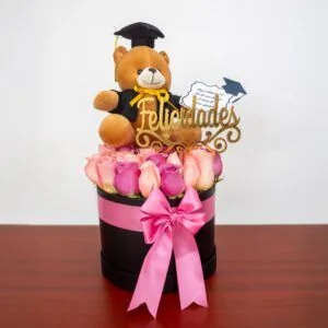 Caja decorativa con rosas rosadas y osito graduado, ideal para celebrar logros académicos con estilo y elegancia.