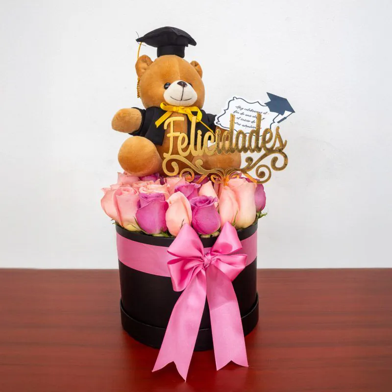Caja decorativa con rosas rosadas y osito graduado, ideal para celebrar logros académicos con estilo y elegancia.