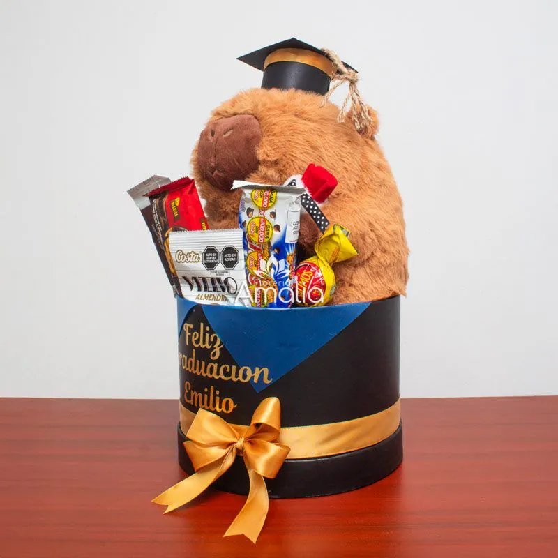 Caja de graduación personalizada con peluche de capibara, dulces variados y mensaje especial, ideal para celebrar logros académicos.