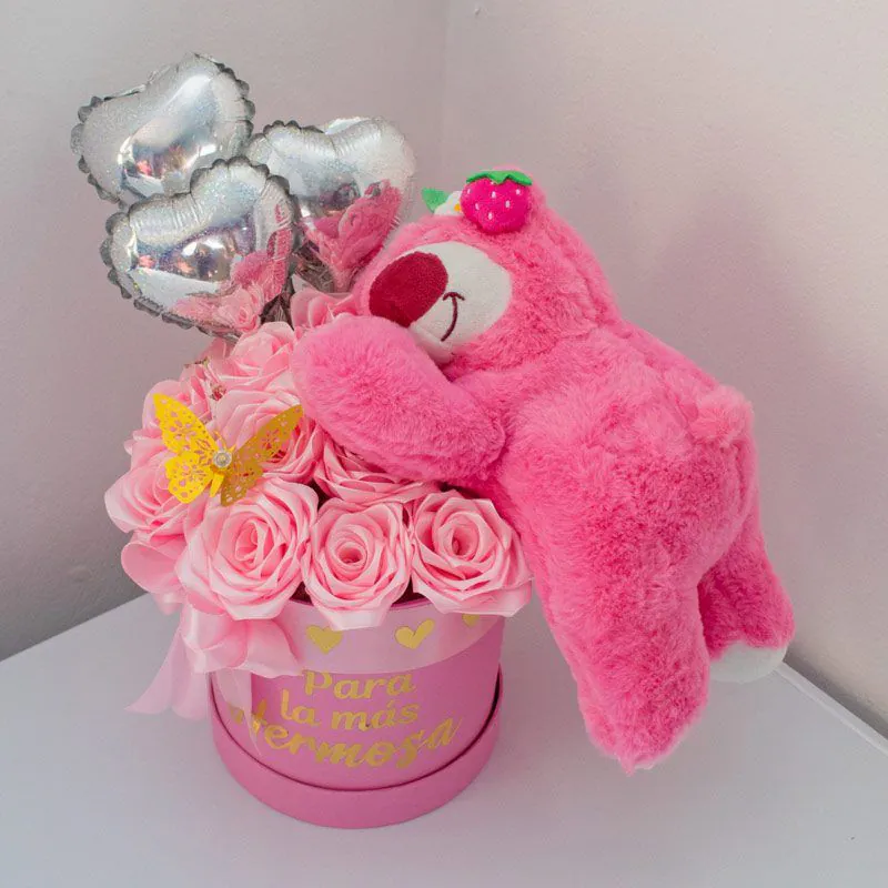 Arreglo floral con peluche rosa tipo Lotso, rosas rosadas, globos metálicos en forma de corazón y caja personalizada con la frase “Para la más hermosa”.