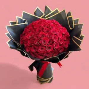 Ramo de 75 rosas rojas naturales envuelto en papel negro con bordes dorados, ideal para sorprender con un regalo elegante y apasionado.