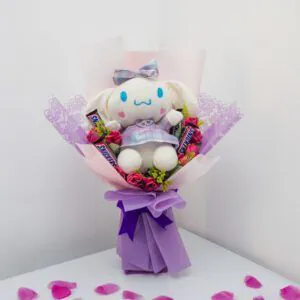Ramo con peluche Cinnamoroll, rosas rosadas y chocolates Snickers, envuelto en papel lila con lazo decorativo, ideal para sorprender con ternura.