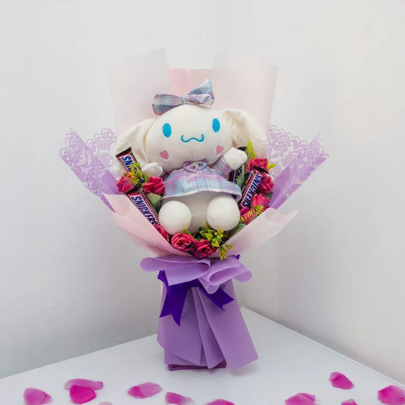 Ramo con peluche Cinnamoroll, rosas rosadas y chocolates Snickers, envuelto en papel lila con lazo decorativo, ideal para sorprender con ternura.