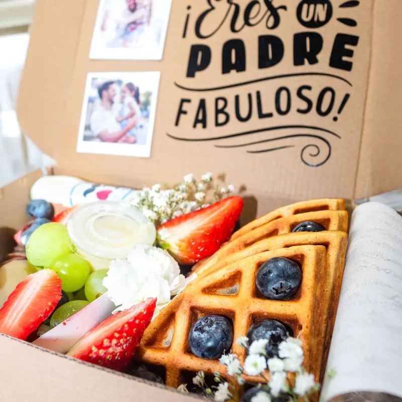 Desayuno sorpresa para papá con mensaje “¡Eres un padre fabuloso!”, waffles, frutas frescas y pétalos de rosas azules.
