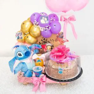 “Cumpleaños sorpresa con peluche Stitch, torta decorada, globo burbuja, arco de globos y fotos personalizadas sobre base, ideal para regalar.”