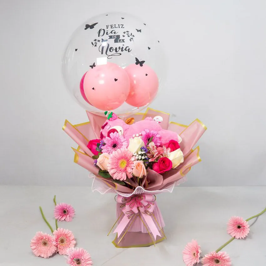 Arreglo con globo burbuja “Feliz Día de la Novia”, peluche rosado y bouquet de gerberas y rosas en tonos pastel.