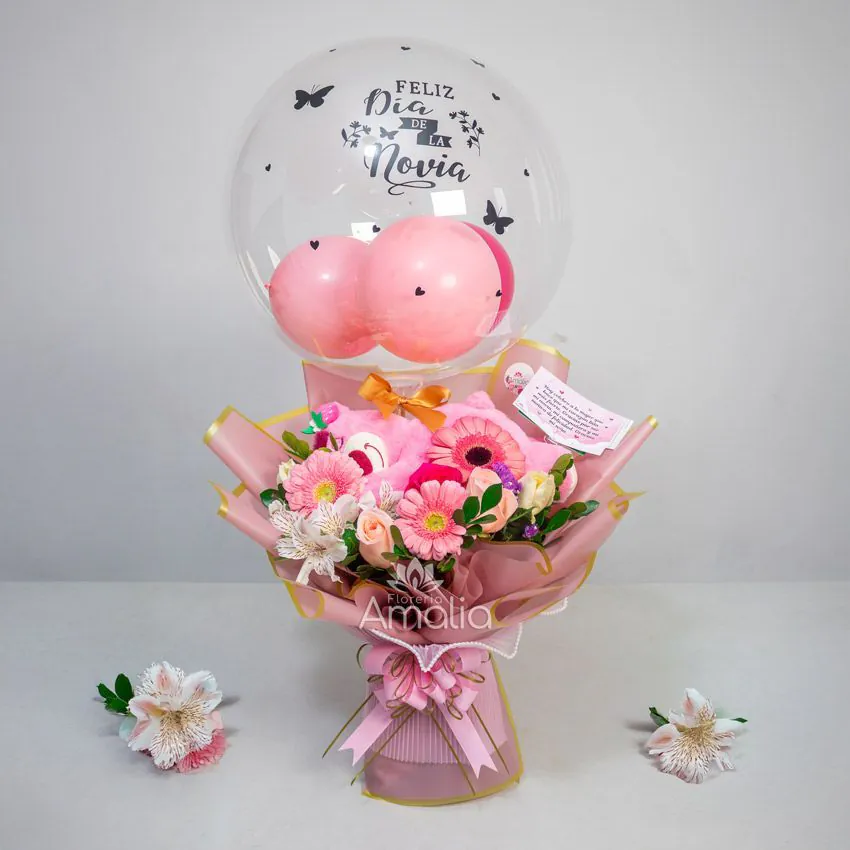 Arreglo con globo burbuja “Feliz Día de la Novia”, peluche rosado y bouquet de gerberas y rosas en tonos pastel.
