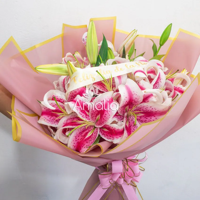 Ramo de lirios Stargazer rosados envueltos en papel rosa con cinta “Feliz Día de la Novia”.