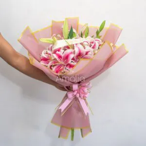 Ramo de lirios Stargazer rosados envueltos en papel rosa con cinta “Feliz Día de la Novia”.