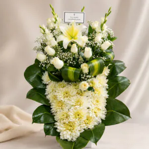 Arreglo fúnebre blanco con lirios, rosas blancas y follaje verde de Florería Amalia
