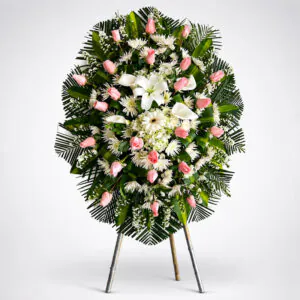 Corona fúnebre con rosas rosadas, flores blancas, lirios y follaje verde de Florería Amalia