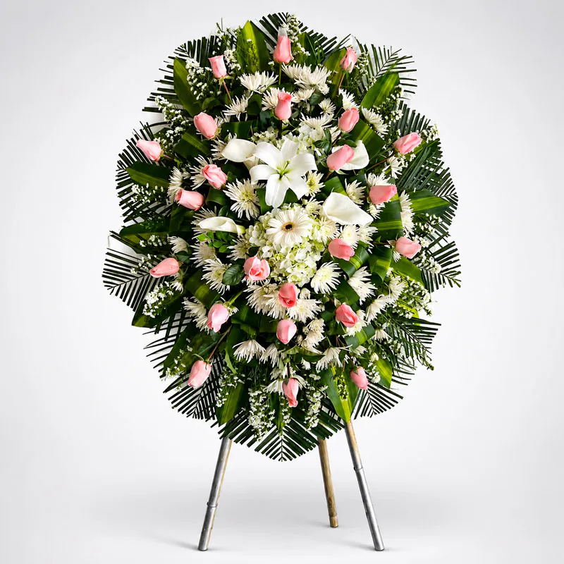 Corona fúnebre con rosas rosadas, flores blancas, lirios y follaje verde de Florería Amalia