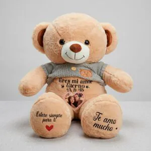 Oso de peluche beige con suéter gris, personalizado con foto de pareja en el vientre y mensajes de amor en las patas.