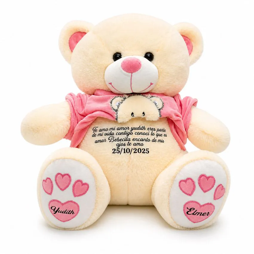 Oso de peluche tierno con polera rosa levantada, mostrando un mensaje oculto de amor en el pecho y huellas rosas con los nombres Yudith y Elmer en las patitas.