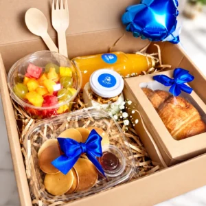 Caja con pancakes, croissant y globo corazón azul.