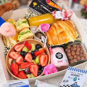 Caja con sándwiches, croissant, frutas, yogurt y cereal.