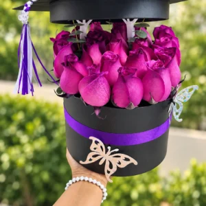 Logro Violeta: Rosas en tonos morados en una caja negra con cinta violeta.