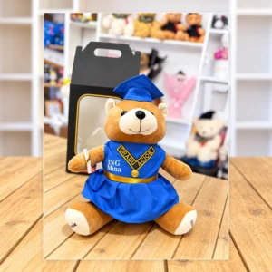 Osita con toga y birrete azul, estola dorada, medalla y diploma. Incluye empaque de regalo con ventana.