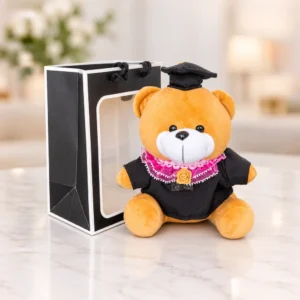 Osito color miel con toga negra, cuello rosa, birrete y medalla. Incluye bolsa de regalo con ventana.