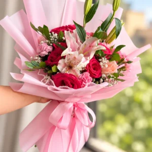 Ramo de rosas y lirios rosados con lazo rosa.