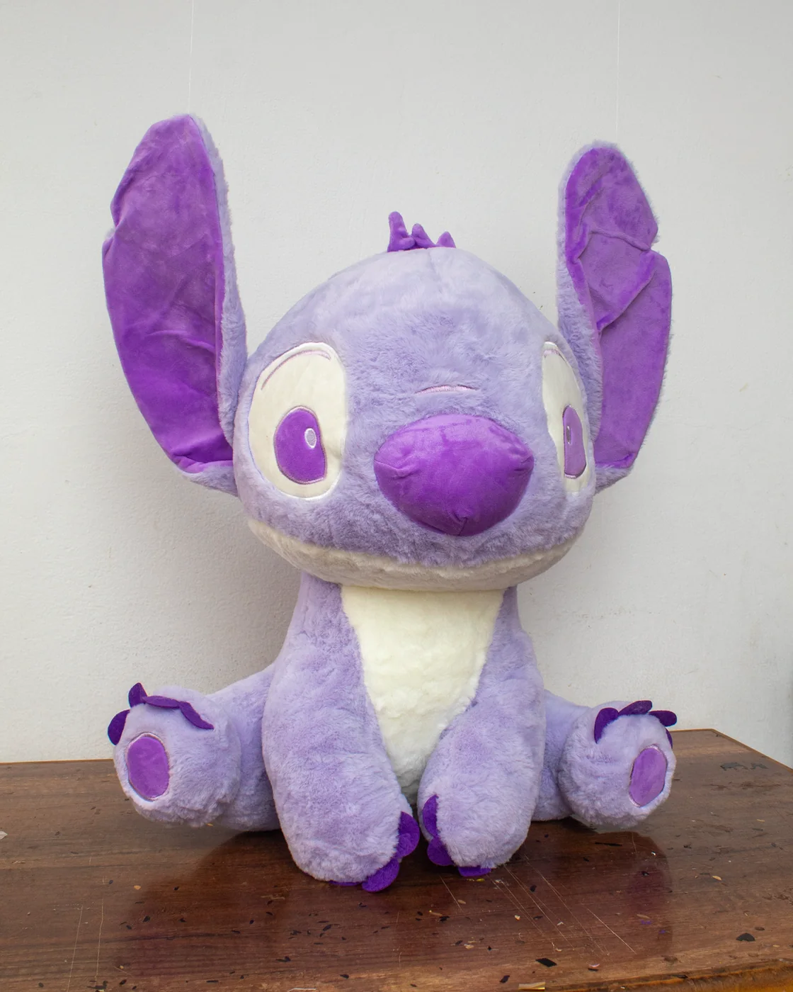 Peluche Stitch lila con barriga clara y detalles violetas.