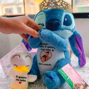 Stitch con corona dorada, patito y tarjeta de dedicatoria.